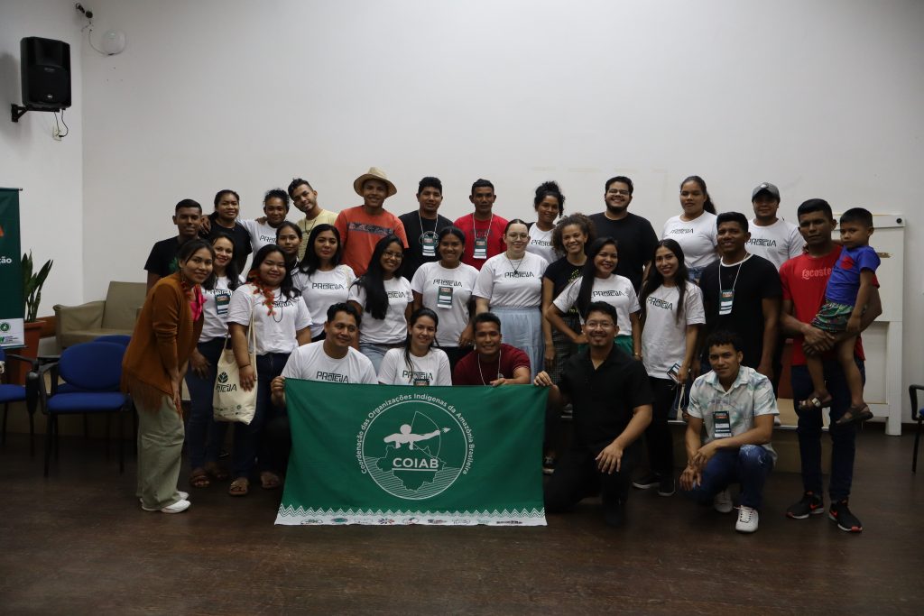 Várias pessoas indígenas e extrativistas olham para a câmera e sorriem.