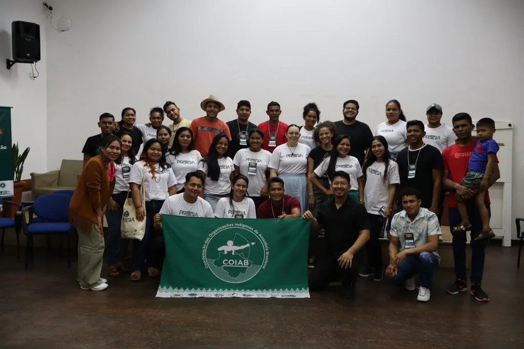 Várias pessoas indígenas e extrativistas olham para a câmera e sorriem.